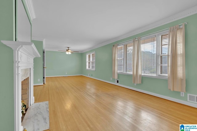 unfurnished living room featuring ceiling fan, wood-type flooring, a premium fireplace, and crown molding