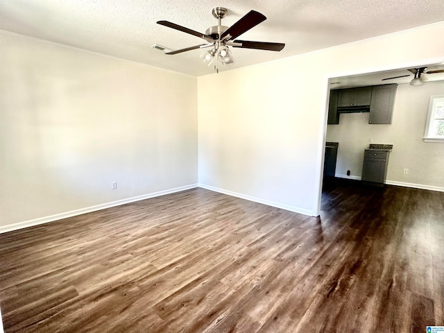 empty room featuring a textured ceiling, ceiling fan, and dark wood-type flooring