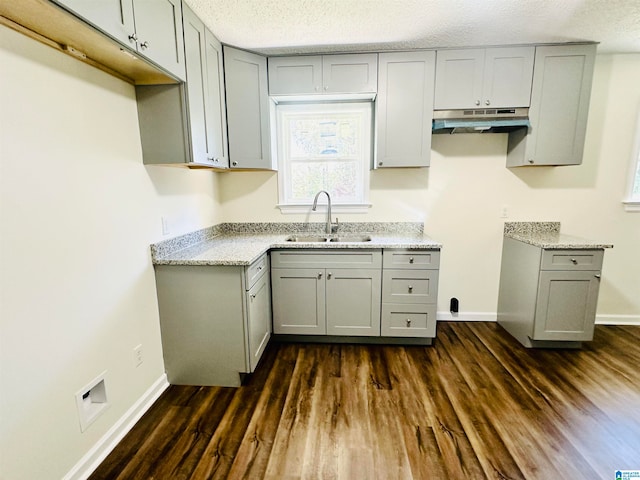 kitchen with a textured ceiling, dark hardwood / wood-style flooring, gray cabinets, and sink