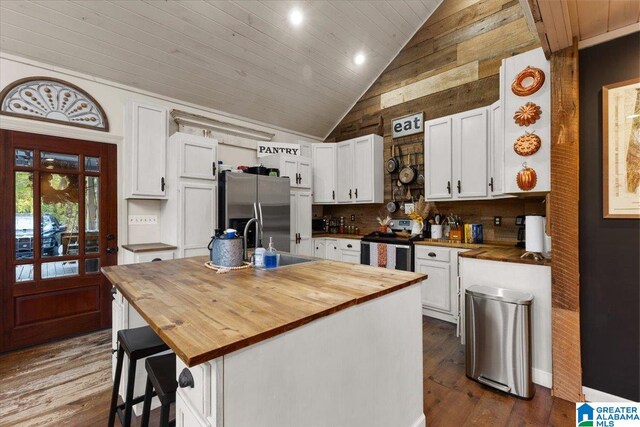 kitchen featuring wooden counters, appliances with stainless steel finishes, a kitchen island with sink, dark wood-type flooring, and white cabinetry