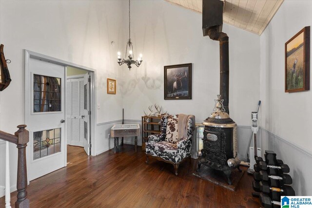 sitting room with a wood stove, wooden ceiling, high vaulted ceiling, dark hardwood / wood-style floors, and a notable chandelier