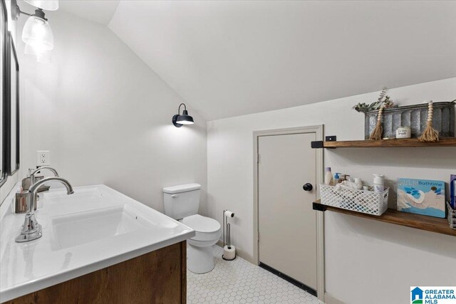 bathroom featuring toilet, vanity, and vaulted ceiling