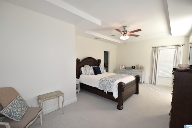 carpeted bedroom featuring a raised ceiling and ceiling fan