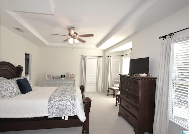 carpeted bedroom with a tray ceiling and ceiling fan