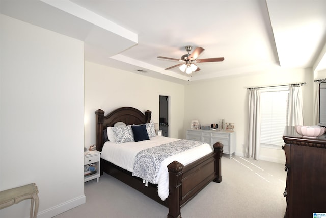 carpeted bedroom with a tray ceiling and ceiling fan