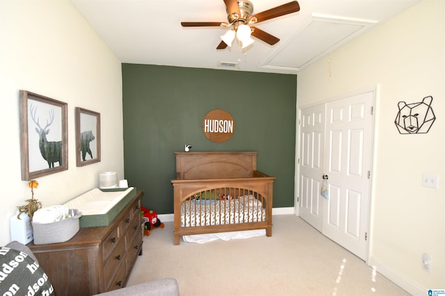 bedroom with ceiling fan, a closet, light colored carpet, and a crib