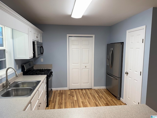 kitchen featuring white cabinets, appliances with stainless steel finishes, light hardwood / wood-style floors, and sink