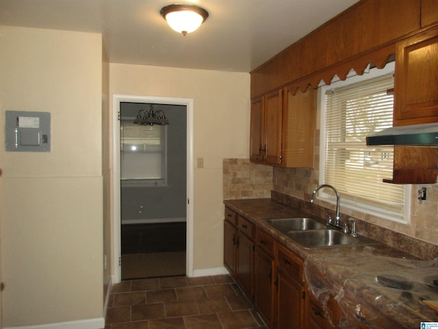 kitchen featuring electric panel, ventilation hood, dark tile patterned flooring, sink, and decorative backsplash