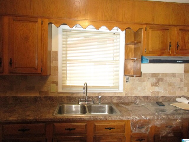 825 Goldwire St SW, Birmingham, AL 35211 - kitchen featuring a sink, brown cabinetry, under cabinet range hood, and backsplash