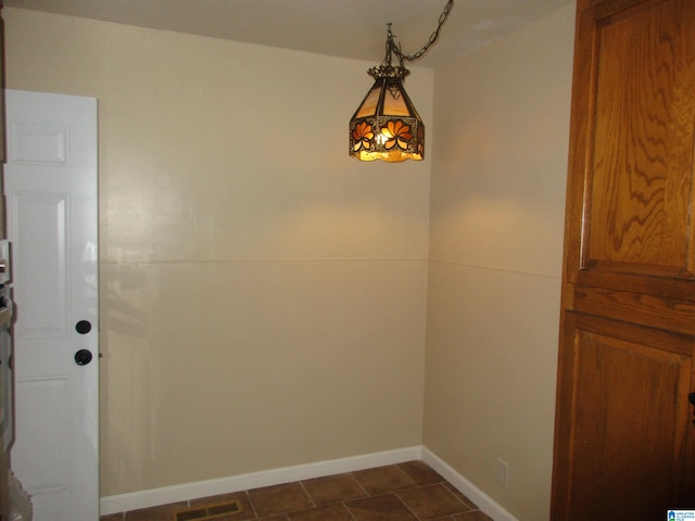 unfurnished dining area featuring dark tile patterned flooring