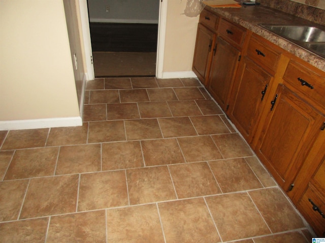 825 Goldwire St SW, Birmingham, AL 35211 - kitchen featuring baseboards, brown cabinetry, and a sink