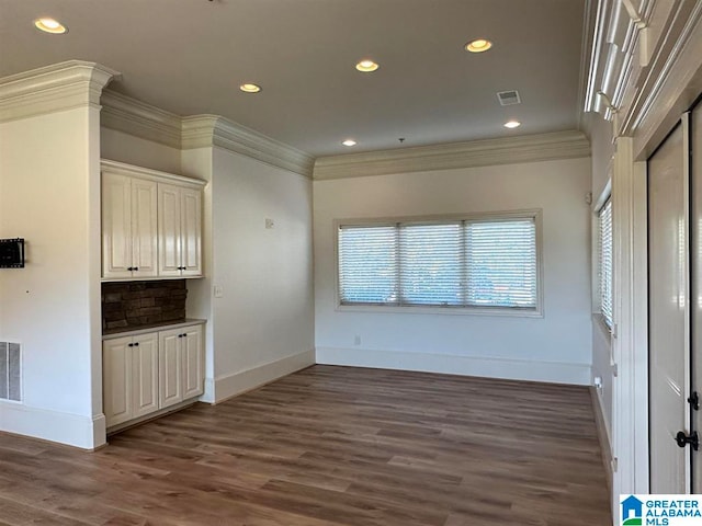 unfurnished dining area with ornamental molding and dark wood-type flooring