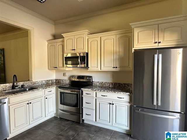 kitchen featuring crown molding, sink, dark stone countertops, dark tile patterned floors, and appliances with stainless steel finishes