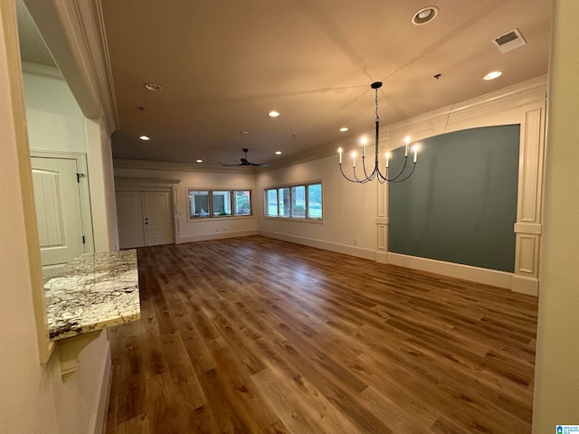 interior space with ceiling fan with notable chandelier, dark hardwood / wood-style flooring, and ornamental molding