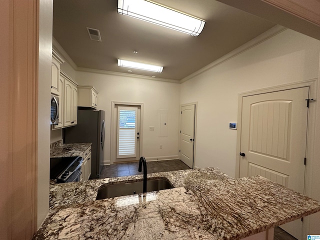 kitchen with sink, dark tile patterned floors, ornamental molding, appliances with stainless steel finishes, and kitchen peninsula