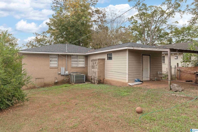 rear view of property featuring a lawn and cooling unit