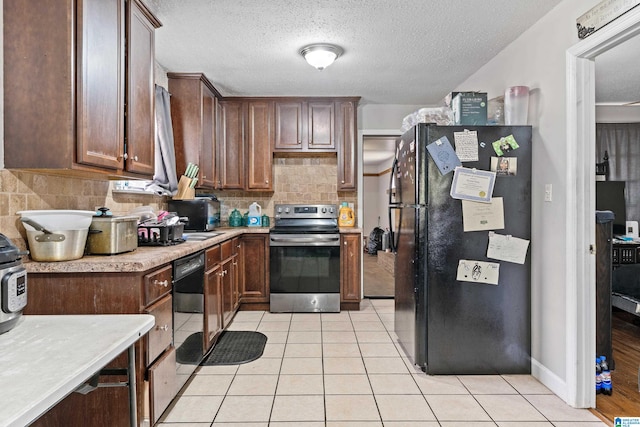 kitchen with backsplash, light tile patterned floors, black appliances, and a textured ceiling