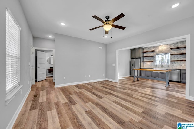 unfurnished living room featuring ceiling fan, light hardwood / wood-style flooring, and sink