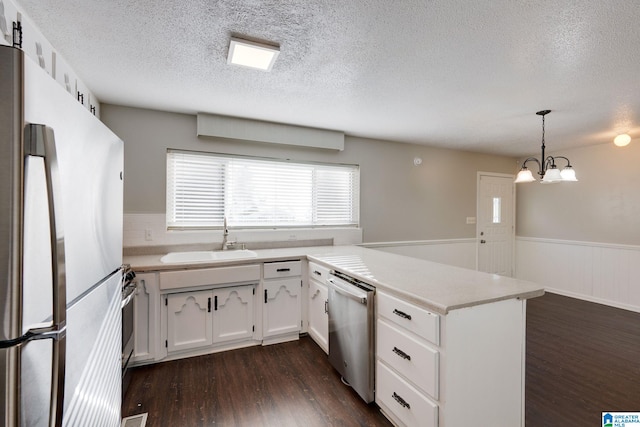 kitchen with pendant lighting, sink, dark hardwood / wood-style floors, kitchen peninsula, and stainless steel appliances