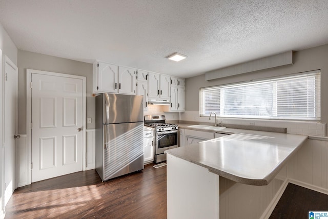 kitchen with white cabinetry, sink, stainless steel appliances, dark hardwood / wood-style floors, and kitchen peninsula