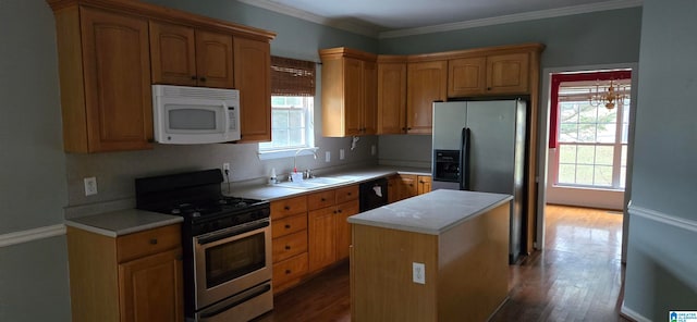 kitchen with a center island, sink, crown molding, hardwood / wood-style flooring, and stainless steel appliances