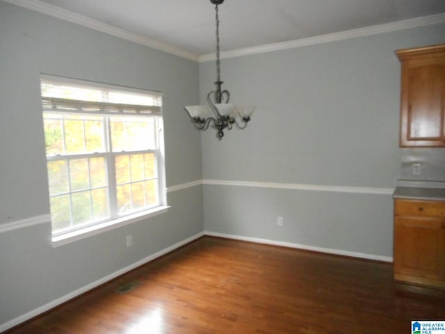 unfurnished dining area with a chandelier, crown molding, and dark wood-type flooring