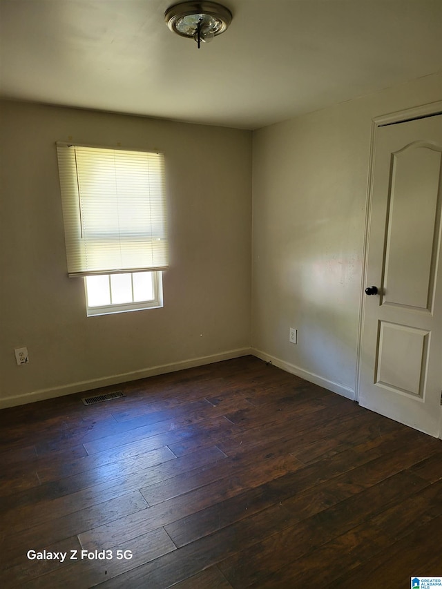 unfurnished room with dark hardwood / wood-style flooring