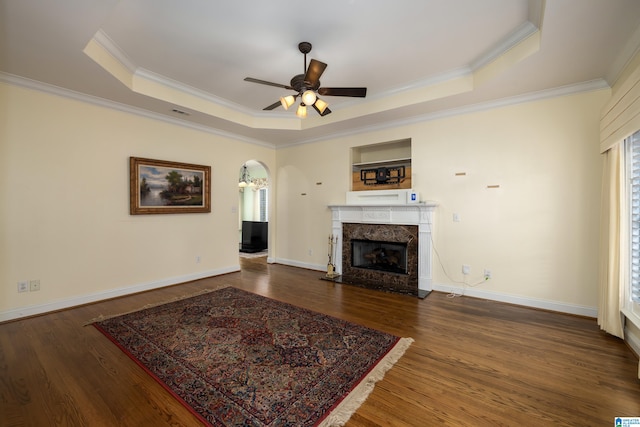 living room with dark hardwood / wood-style floors, crown molding, a high end fireplace, and a tray ceiling