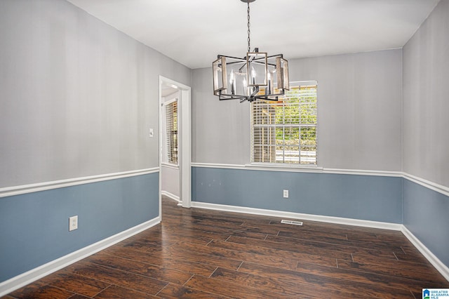 spare room featuring dark hardwood / wood-style flooring and a chandelier