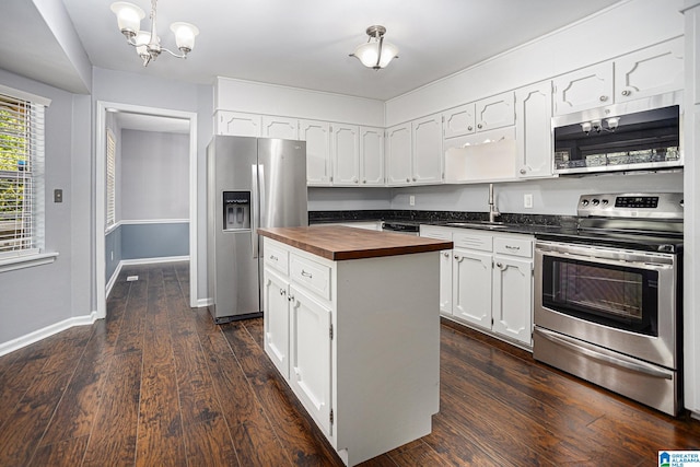 kitchen featuring butcher block countertops, sink, white cabinetry, stainless steel appliances, and a center island