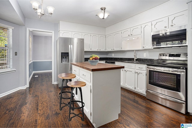 kitchen featuring a breakfast bar, wooden counters, white cabinetry, stainless steel appliances, and a center island