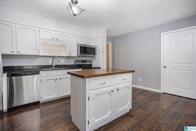 kitchen featuring a kitchen island, appliances with stainless steel finishes, white cabinetry, sink, and wooden counters