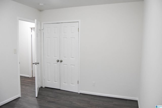 unfurnished bedroom featuring a closet and dark hardwood / wood-style flooring