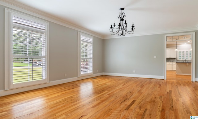 empty room with a chandelier, light hardwood / wood-style flooring, ornamental molding, and sink