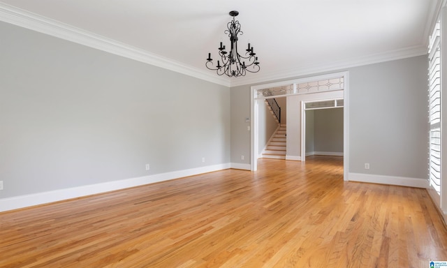 spare room featuring crown molding, light hardwood / wood-style floors, and an inviting chandelier