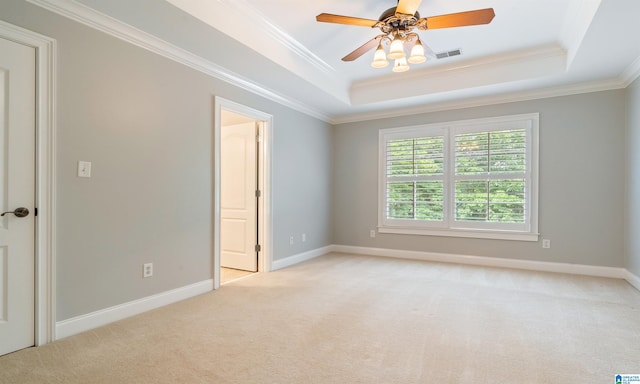 spare room with ceiling fan, ornamental molding, light carpet, and a tray ceiling