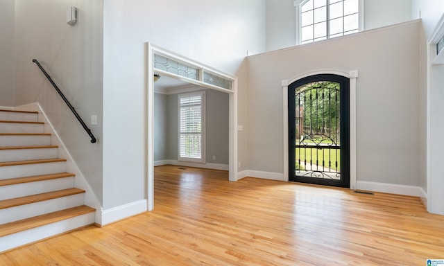 entryway with plenty of natural light, a towering ceiling, and light hardwood / wood-style floors