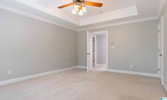 spare room with a tray ceiling, crown molding, ceiling fan, and light colored carpet