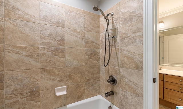 bathroom featuring crown molding, vanity, and tiled shower / bath