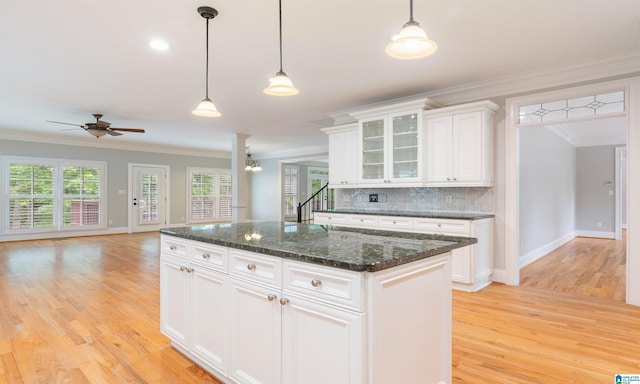 kitchen featuring ornamental molding, a kitchen island, light hardwood / wood-style floors, white cabinetry, and hanging light fixtures