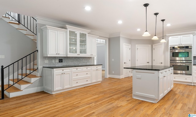 kitchen featuring white cabinets, a kitchen island, stainless steel double oven, and light hardwood / wood-style flooring