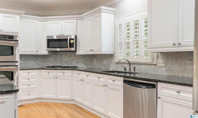 kitchen featuring dark stone countertops, sink, white cabinets, and stainless steel appliances