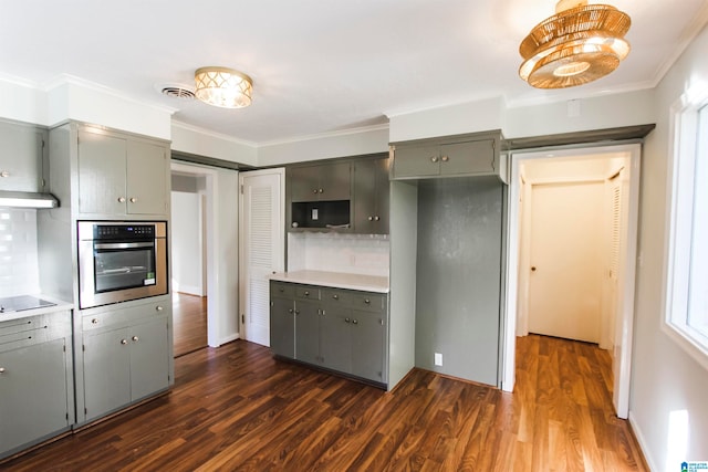 kitchen featuring backsplash, dark hardwood / wood-style flooring, stainless steel oven, and ornamental molding