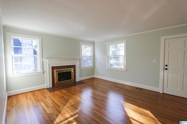 unfurnished living room with hardwood / wood-style floors, ornamental molding, a textured ceiling, and a brick fireplace