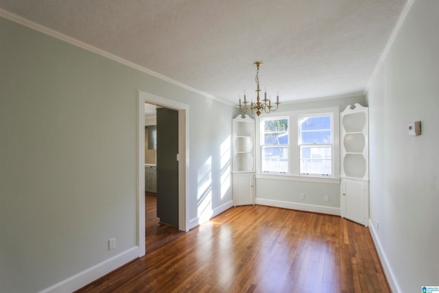 unfurnished dining area with dark hardwood / wood-style flooring, an inviting chandelier, a textured ceiling, and ornamental molding