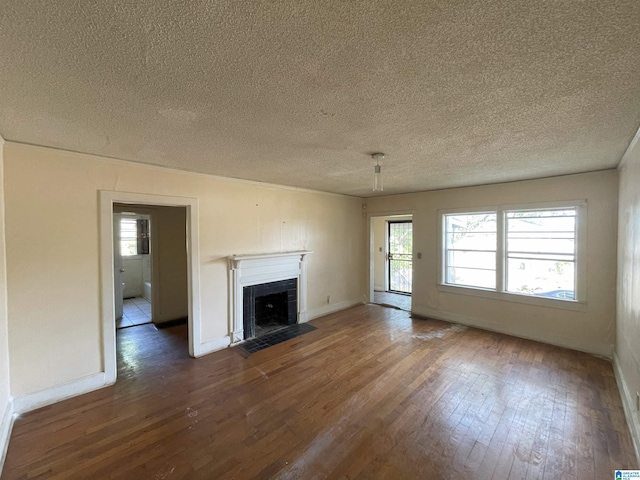 unfurnished living room featuring a textured ceiling, dark hardwood / wood-style floors, plenty of natural light, and a tiled fireplace