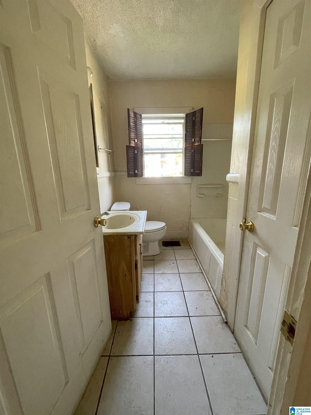 bathroom with vanity, a bathtub, tile patterned floors, toilet, and a textured ceiling