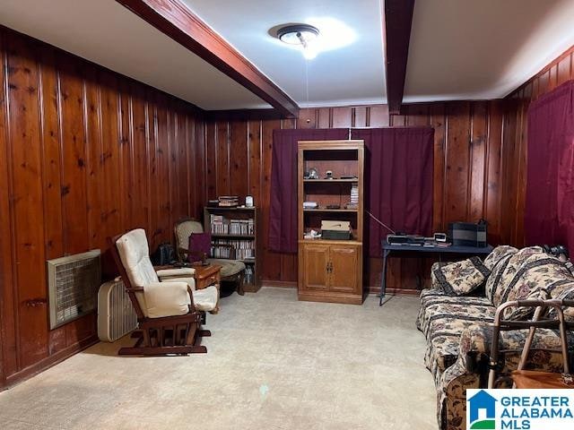 sitting room featuring heating unit, light colored carpet, beamed ceiling, and wood walls