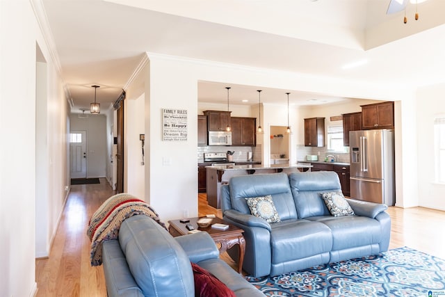 living room featuring ceiling fan, light hardwood / wood-style floors, and ornamental molding