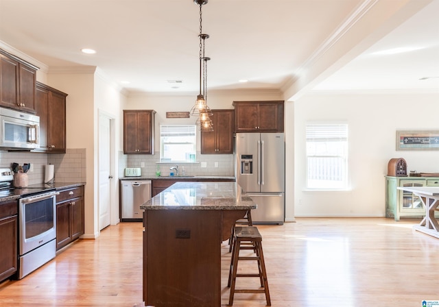 kitchen featuring appliances with stainless steel finishes, a center island, light hardwood / wood-style flooring, and dark stone countertops